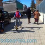 Niños con patinete sobre acera