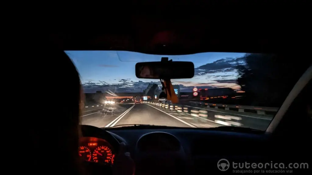 Conductora en el interior del vehículo en una carretera de noche. Procesamiento automático y controlado de la información al conducir